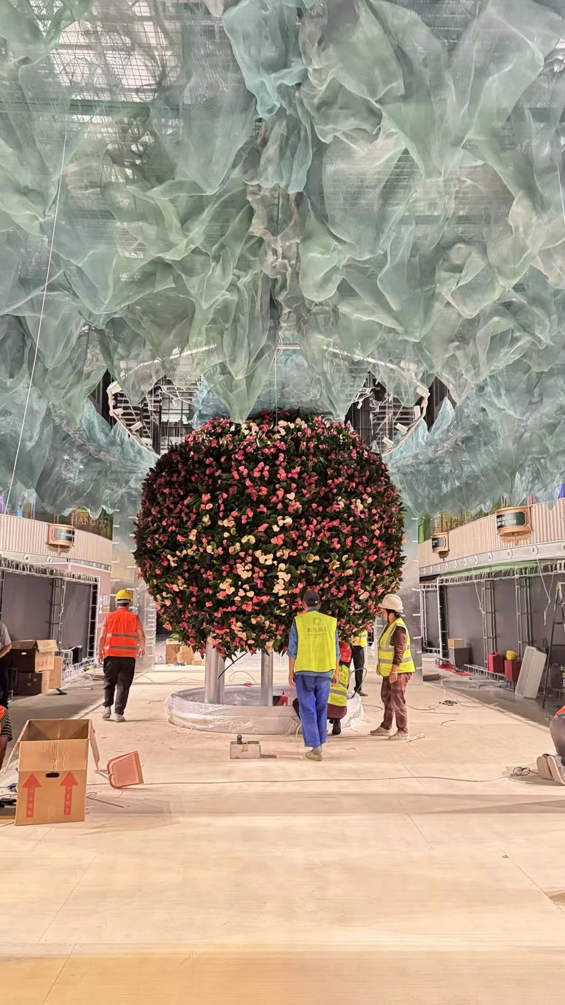 The real floral sphere being installed at M Focus, with the production team beneath the textile canopy